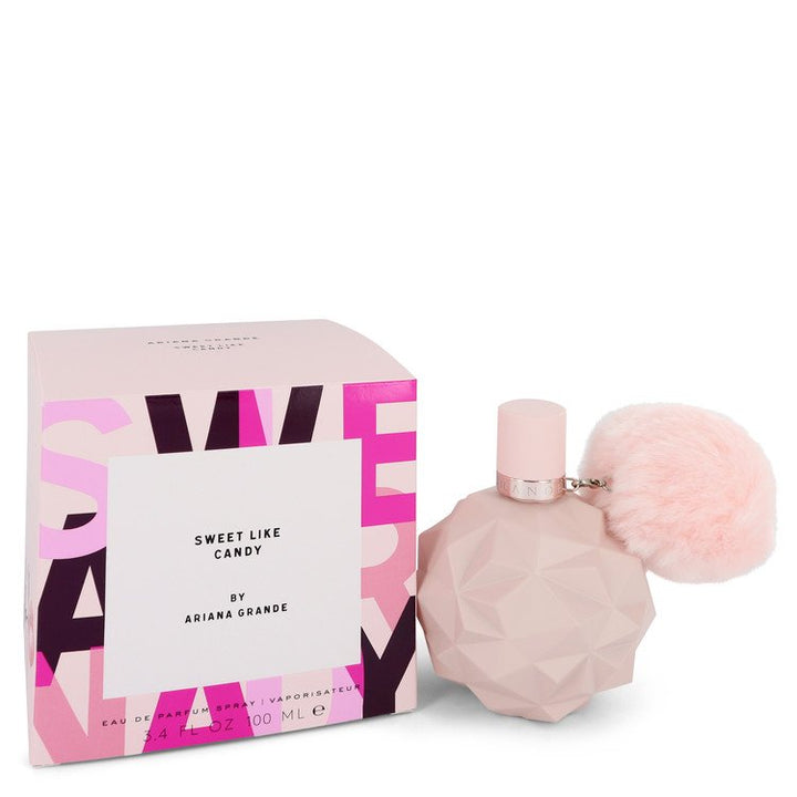 Perfume bottle with pink cap and pom-pom next to its packaging on a white background